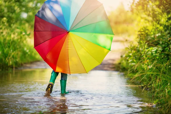 少年はカラフルな傘を手に水溜りを歩いている 幸福の概念 — ストック写真