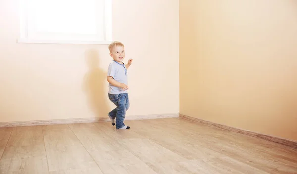 Smiling boy running in empty light room. Concept of family relocation, rental apartment and home ownership.