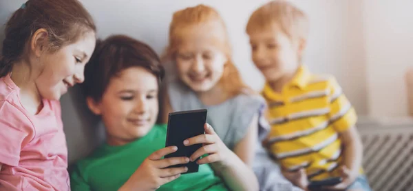 屋内に座ってスマートフォンを見ている子供たちのグループ スマート技術の使用の概念 — ストック写真