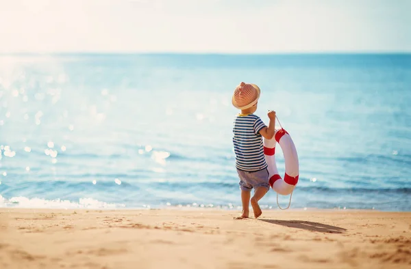 彼の手だけで海辺を歩いてライフブイと小さな男の子 家族の休暇と観光の概念 — ストック写真
