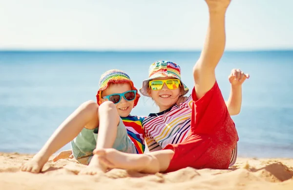 男孩和女孩坐在海边的沙滩上 家庭假期和旅游的概念 — 图库照片