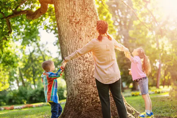 家人牵着手在自然公园的大树旁玩耍 爱情和关系概念 免版税图库图片