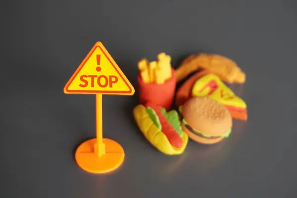 Closeup image of STOP signboard and junk foods. Stop eating unhealthy food concept.