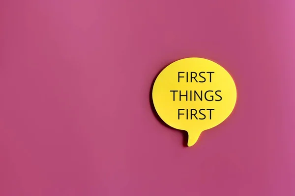 Top view image of speech bubble with text FIRST THINGS FIRST on pink background with copy space