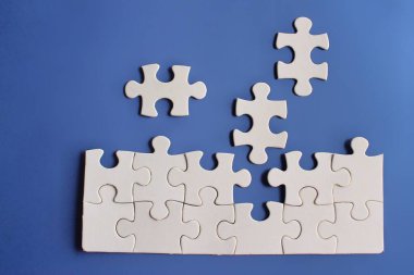 Mavi arkaplandaki eksik yapbozun üst görünüm resmi.