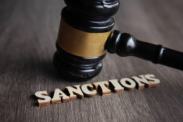 Yargıç Tokmak 'ın resmini kapat ve ahşap masaya SANCTIONS' u yaz.