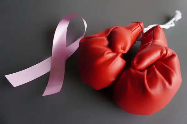 Close up image of boxing gloves and pink ribbon. Breast cancer awareness, cancer survivor concept