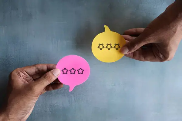 Hand holding speech bubble with star review icon. Customer feedback and satisfaction concept.