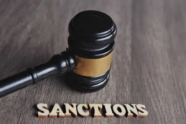 Yargıç Tokmak 'ın resmini kapat ve ahşap masaya SANCTIONS' u yaz.
