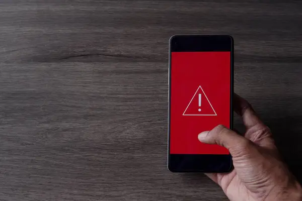 Smartphone with triangle caution warning icon. Copy space for text. System error, malware and cyber crime concept.