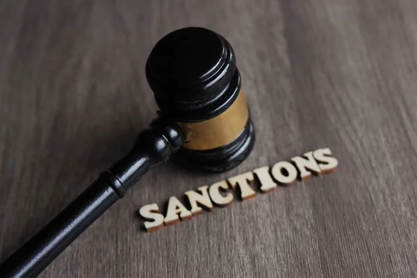 Yargıç Tokmak 'ın resmini kapat ve ahşap masaya SANCTIONS' u yaz.