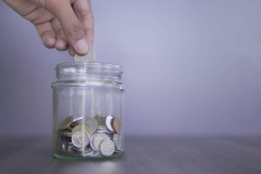 El, bozuk para dolu bir kavanoza bozuk para koyuyor. Uzayı metin için kopyala. Tasarruf etmek, emeklilik planı.