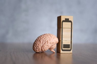 Closeup image of brain and wooden blocks with low energy battery icon. Exhausted, tired and burnout concept. clipart