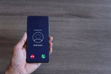 Akıllı telefonu tutan el görüntüsü ve ekranda bilinmeyen bir arama var. Uzayı kopyala Dolandırıcı, dolandırıcılık konsepti.