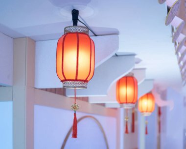 Tavandan sarkan bir sıra turuncu kağıt fener. Fenerler yuvarlaktır ve geleneksel Çin tasarımına sahiptir. İçeriden aydınlatılıyor, sıcak bir parıltı saçıyorlar..