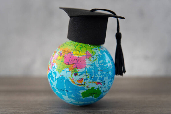 Graduation cap on top of world globe with copy space. Study abroad. foreign students concept.