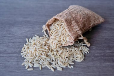 Tahta masada üzerinde fotokopi alanı olan küçük çuval içinde kahverengi pirinç resmi..