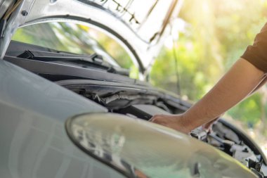 Arabanın motorunu inceleyen ve kontrol eden adamın yakın plan görüntüsü. Ulaşım kavramı.