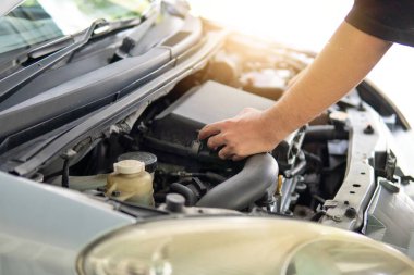 Arabanın motorunu inceleyen ve kontrol eden adamın yakın plan görüntüsü. Ulaşım kavramı.