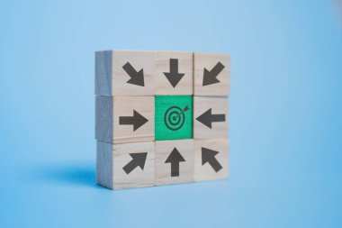 Mavi arka plandaki hedef merkezini gösteren çeşitli oklarla dolu tahta bloklar. Hedef, hedef ve yön kavramı.