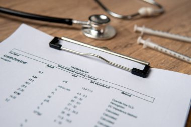 Tahtada hematoloji raporu ve stetoskop olan bir panonun yakın plan görüntüsü..
