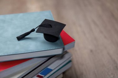 Renkli kitapların üzerinde siyah bir mezuniyet şapkası. Uzayı metin için kopyala. Eğitim ve bilgi kavramı.