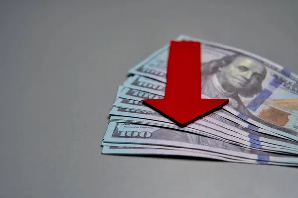 Bir yığın Amerikan dolarının tepesini işaret eden kırmızı bir ok. Ekonomik durgunluk, finansal düşüş, ekonomik kriz kavramı.