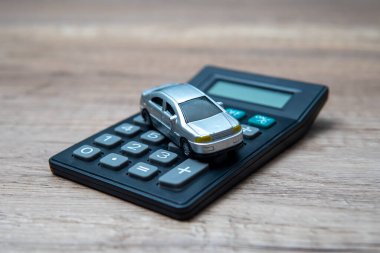 Hesap makinesinin tepesindeki oyuncak araba, araba sahibi olmanın finansal yönlerini simgeliyor..