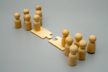 Yapboz parçası köprüsünün iki farklı tarafında duran ahşap figürler grubu. Birleşmeler ve kazançlar, iş bütünleşmesi ve güçlerin birleştirilmesi konsepti.