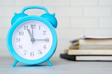 Mavi bir çalar saat ve yığınla kitap. Zaman yönetimi, öğrenim kavramı.