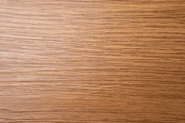 Açık kahverengi ahşap bir yüzeyin yukarıdan aşağı görüntüsü, yatay çizgilerle doğal tahıl desenlerini ve ton çeşitliliklerini gözler önüne seriyor..