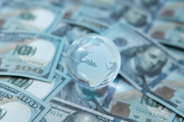 Şeffaf bir küre ve 100 dolarlık banknotlar. Küresel finans kavramı.