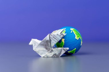 Bir origami kuşu bir Amerikan doları ve bir küreden katlandı. Küresel finans, uluslararası ticaret ve dünya çapında para akışı.