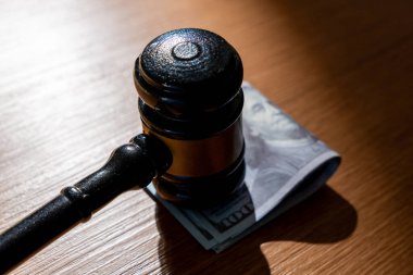 Bir yığın yüz dolarlık banknot ve bir tokmak. Rüşvet, yolsuzluk veya para kavramını içeren yasal anlaşmalar.