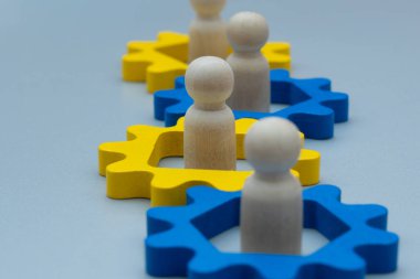 Wooden figures inside interconnected gears. Teamwork, collaboration, and the interconnected nature of work concept.