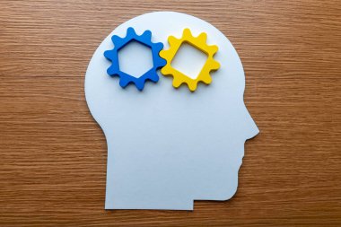 Mavi ve sarı dişlileri olan bir insan kafasının kağıt kesiği. Düşünme, zeka, yaratıcılık ve problem çözme kavramı. 