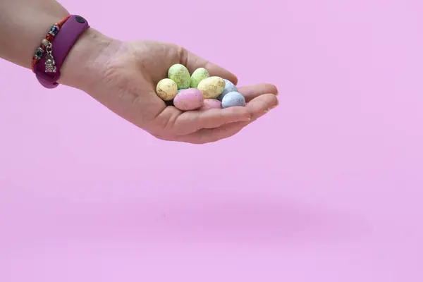 Natural colored quail eggs in a female hand on a pink background. Banner. Close up