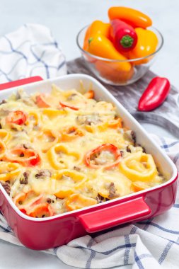 Patatesli güveç, sosis ve renkli dolma biber, bir fırın kabında, dikey