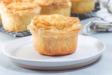 Small beef pot pies on a plate and cooling rack, horizontal