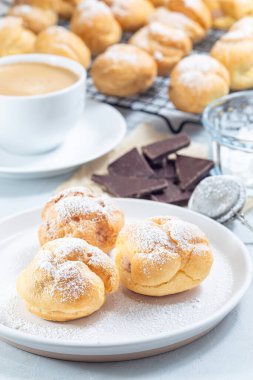 Krem şantili ve çikolatalı ev yapımı profiteroller, krema şekerle kaplı, tabakta, dikey