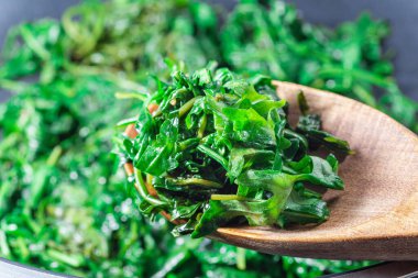 Wilted Arugula ya da roket salatası yakın çekim, zeytinyağında pişirilmiş sarımsak ve balzamik sirke. Biftek için meze hazırlıyorum. Bir tavada, yatay