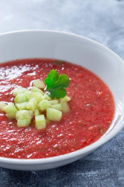 Çorba Gazpacho, salatalık ve kişniş ile süslenmiş, beyaz bir kasede, dikey yakın plan.