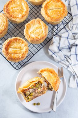 Tabakta dilimlenmiş sığır etli turta ve soğutma rafında turtalar, dikey, üst görünüm