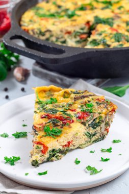 Ispanaklı omlet, kavrulmuş kırmızı biber, mantar, peynir ve otlar tabakta.