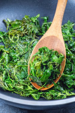 Sarımsak ve balzamik sirkeyle karıştırılmış zeytinyağında pişirilmiş Arugula ya da roket salatası. Kızartma tavasında bir meze hazırlıyorum, dikey.