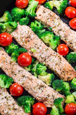 Bir tava, brokoli ve domatesli fırında somon filetosu, dikey, üst manzara, yakın çekim.