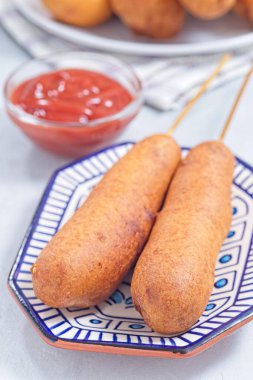 İki sosisli, mavi bir tabakta, ketçapla servis edilmiş, dikey.