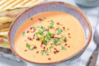 Bowl with a Red bell pepper cream soup, horizontal closeup clipart