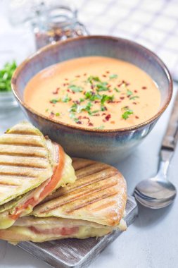 Kırmızı dolmalık biber kremalı çorba, ızgara hindi panini ile servis edilir, dikey.