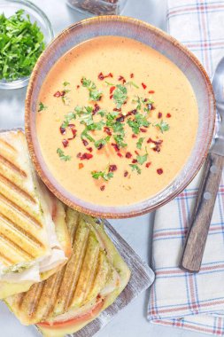 Kavanozda kırmızı biber kremalı çorba, ızgara hindi panini, dikey ızgara hindi panini, dikey üst görünüm.